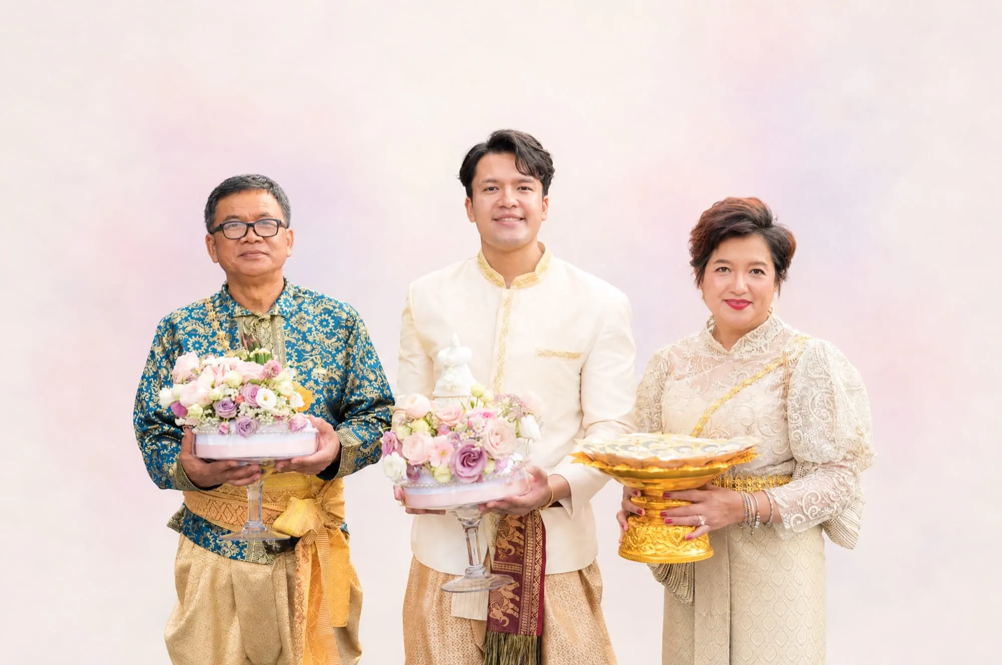 The Wefam family in traditional Thai dress holding flower offerings and a golden tray